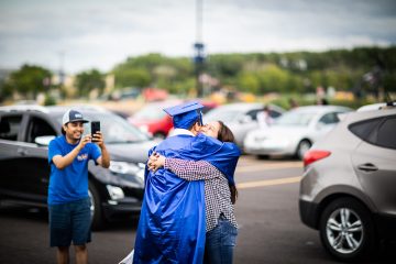 Graduate hugging their family member in celebration.