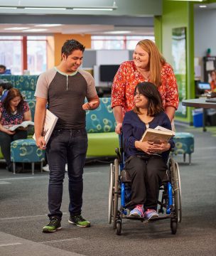 Three WCTC students smiling in conversation, one of which is using a wheelchair.
