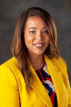 photo of woman looking at camera and smiling wearing yellow blazer